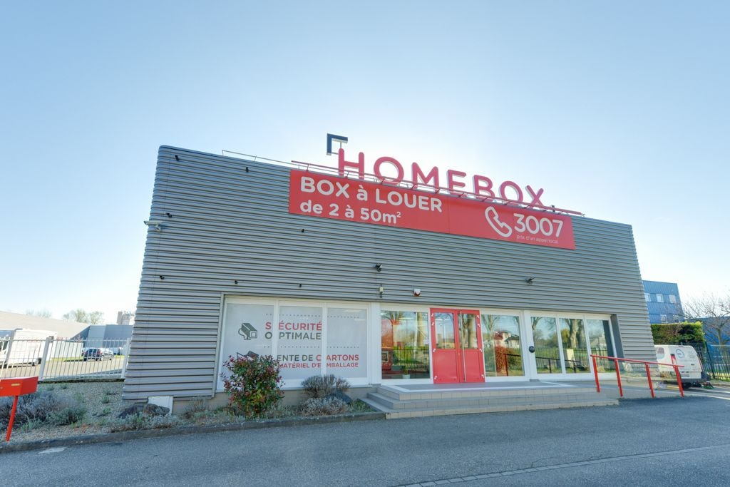 Façade bardée gris clair avec enseigne Homebox et bandeau rouge box à louer, HOMEBOX Strasbourg, 8 rue du Doubs à Strasbourg