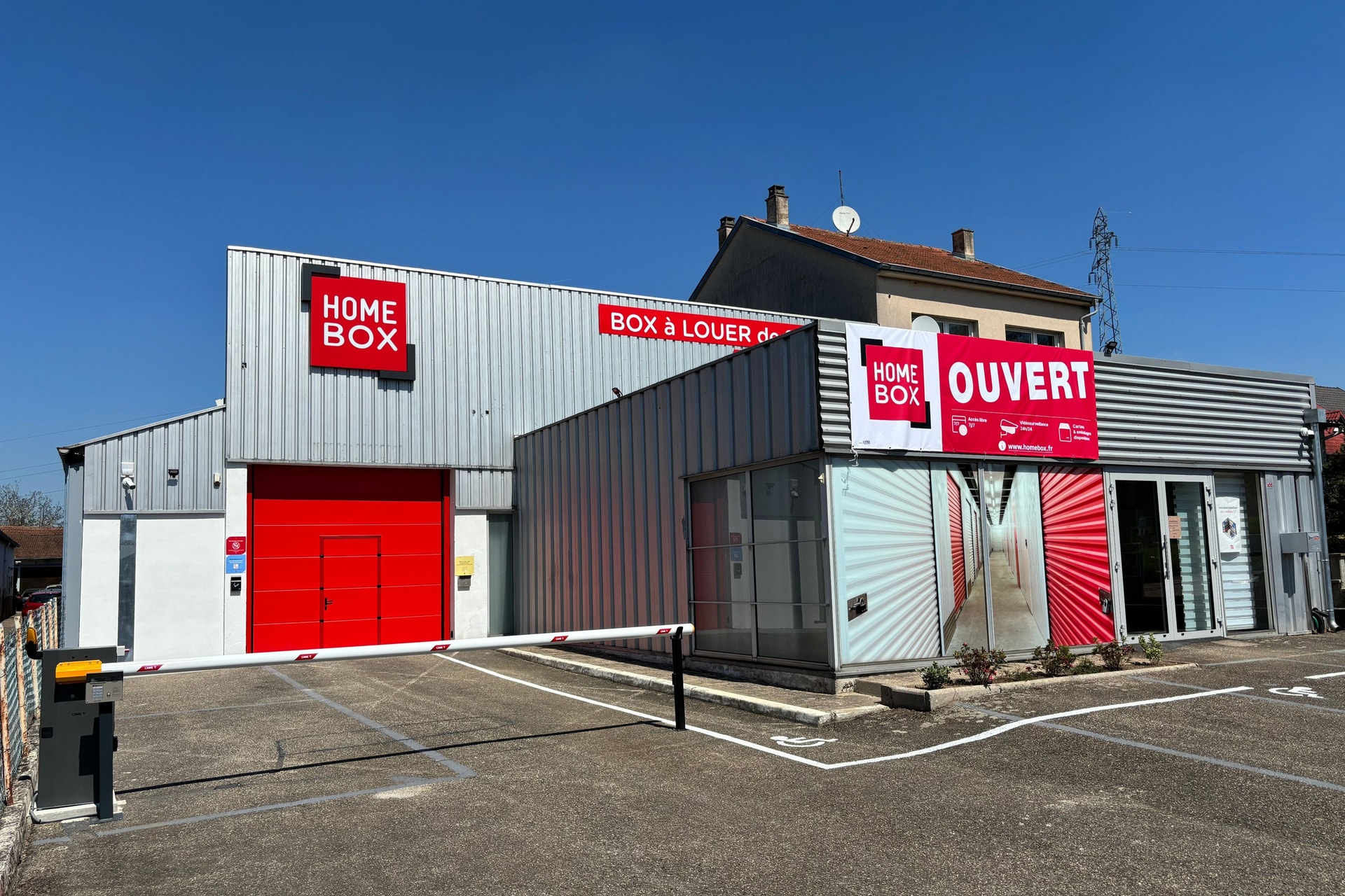 Façade grise avec enseigne rouge HOMEBOX et banderole Ouvert sur parking, HOMEBOX Morsbach, 105 Route Nationale à Morsbach